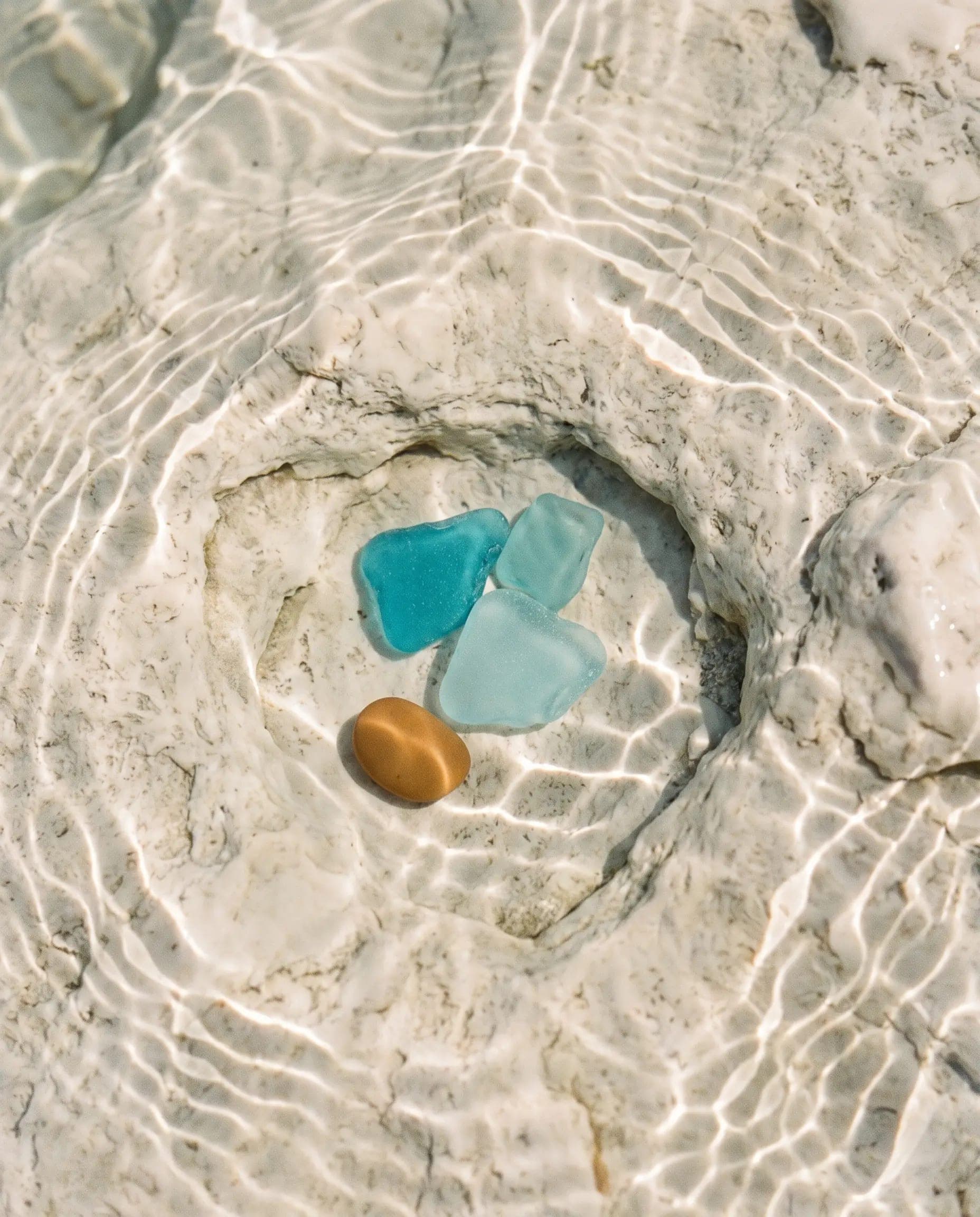 Sunlight through clear water, woven across pale stone and sea glass.