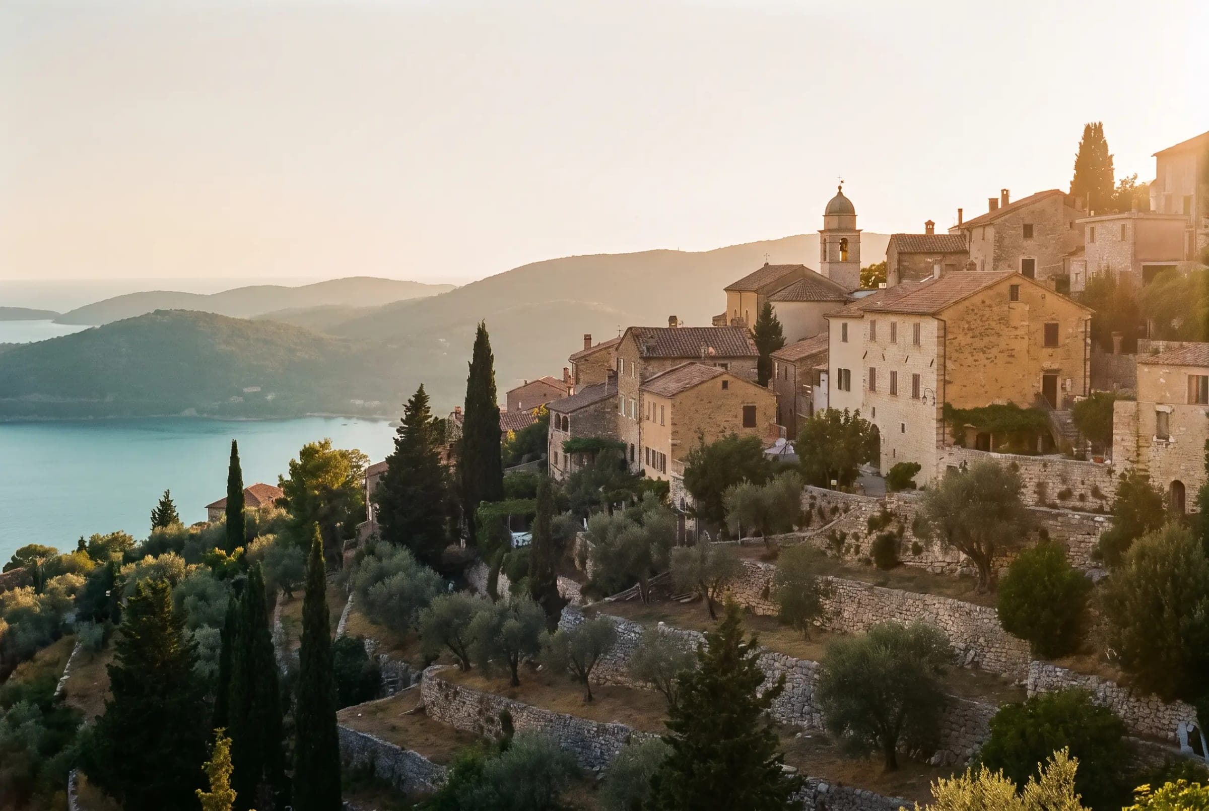 A stone hill village above olive terraces at golden hour.