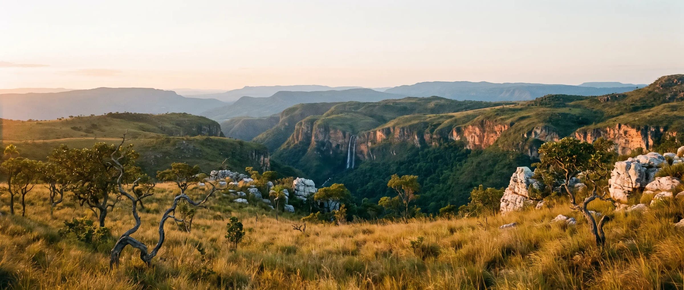 The high plateau of the chapadas at golden hour, a canyon and a waterfall far off.